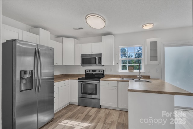 11407 Lenswood Ct, Charlotte, NC 28214 - kitchen with stainless steel appliances, a peninsula, white cabinets, and a textured ceiling