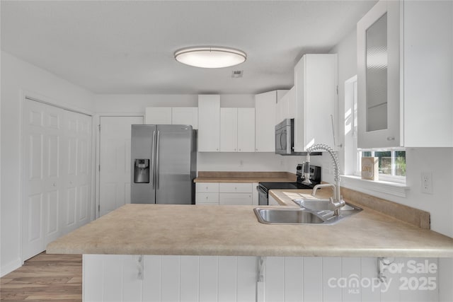 11407 Lenswood Ct, Charlotte, NC 28214 - kitchen featuring stainless steel appliances, a peninsula, light countertops, glass insert cabinets, and white cabinetry