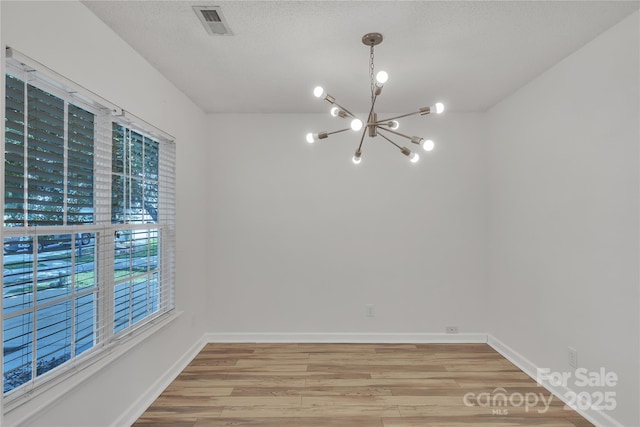 11407 Lenswood Ct, Charlotte, NC 28214 - spare room with a chandelier, light wood-style flooring, and a textured ceiling