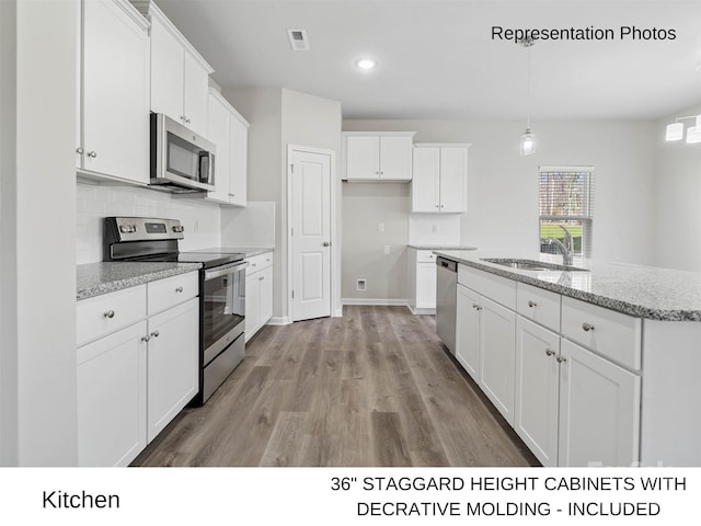 217 Lake George Dr, Shelby, NC 28152 - kitchen featuring stainless steel appliances, white cabinetry, tasteful backsplash, light wood finished floors, and a center island with sink