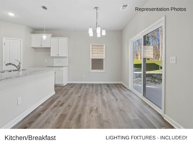 217 Lake George Dr, Shelby, NC 28152 - kitchen with light wood finished floors, white cabinetry, a chandelier, hanging light fixtures, and light stone counters