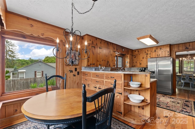 1210 S Main St, Waynesville, NC 28786 - dining area featuring a chandelier, wooden walls, light wood-type flooring, and a textured ceiling