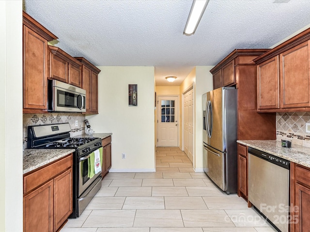 5105 Hampton Meadows Rd, Monroe, NC 28110 - kitchen with stainless steel appliances, decorative backsplash, light stone counters, a textured ceiling, and brown cabinets