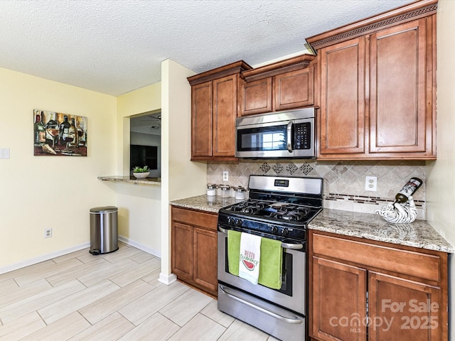 5105 Hampton Meadows Rd, Monroe, NC 28110 - kitchen with stainless steel appliances, decorative backsplash, light stone countertops, brown cabinetry, and a textured ceiling