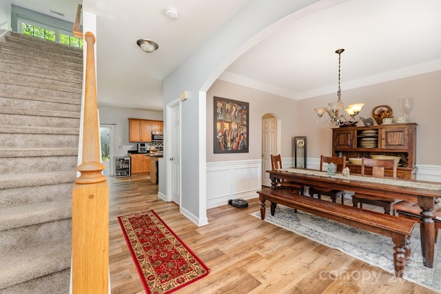 7218 Cascading Pines Dr, Fort Mill, SC 29708 - dining area with arched walkways, stairway, light wood-style flooring, a chandelier, and wainscoting