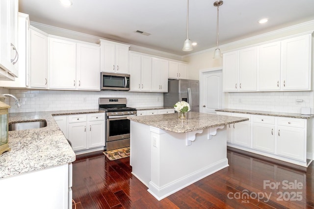 4357 Hornyak Dr, Monroe, NC 28110 - kitchen featuring appliances with stainless steel finishes, white cabinets, dark wood-type flooring, a kitchen island, and decorative backsplash