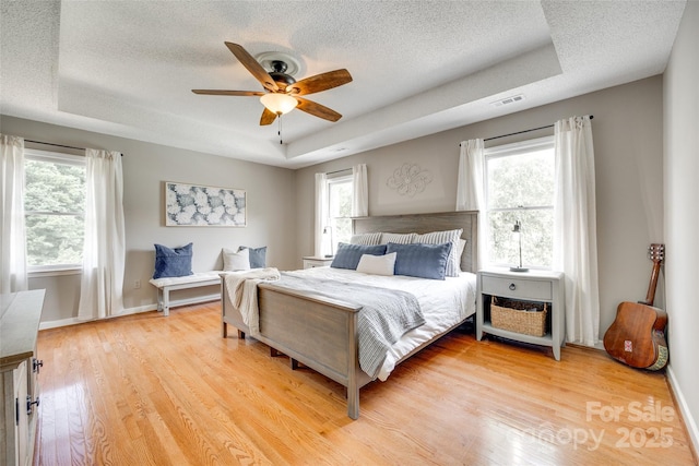 675 Ormand Rd, York, SC 29745 - bedroom with a tray ceiling, light wood-style flooring, a textured ceiling, and a ceiling fan