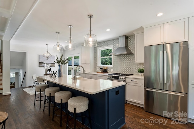 3165 Pendleton Ave, Charlotte, NC 28210 - kitchen featuring stainless steel appliances, wall chimney range hood, dark wood-style floors, backsplash, and a breakfast bar area