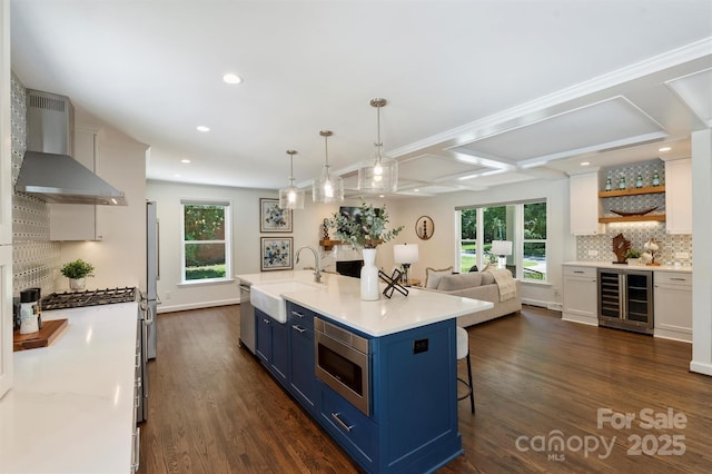 3165 Pendleton Ave, Charlotte, NC 28210 - kitchen featuring blue cabinetry, wall chimney exhaust hood, beverage cooler, appliances with stainless steel finishes, and decorative backsplash