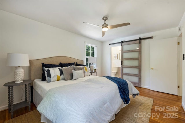 3165 Pendleton Ave, Charlotte, NC 28210 - bedroom with a barn door, wood finished floors, ensuite bathroom, and ceiling fan