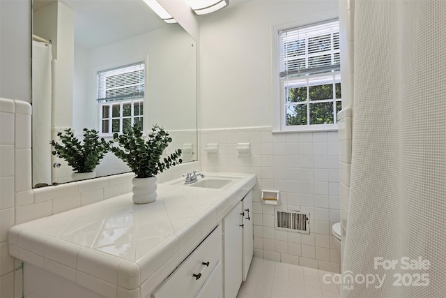 3165 Pendleton Ave, Charlotte, NC 28210 - full bathroom featuring tile walls, vanity, healthy amount of natural light, wainscoting, and tile patterned floors