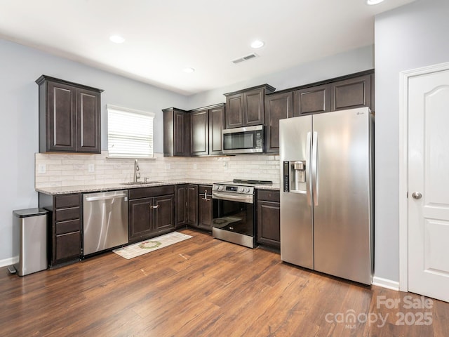 9123 Magnolia Lily Ave, Charlotte, NC 28227 - kitchen featuring appliances with stainless steel finishes, dark brown cabinetry, tasteful backsplash, dark wood finished floors, and light stone counters