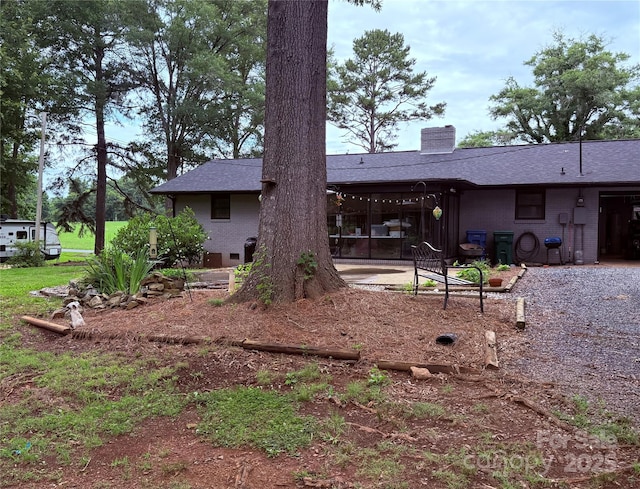 605 Impala Dr, Albemarle, NC 28001 - back of property with a chimney, brick siding, a patio area, and roof with shingles