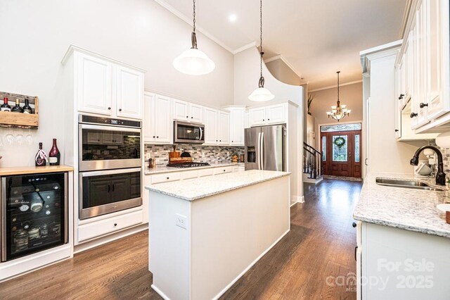 1083 Fox Chase Dr, Newton, NC 28658 - kitchen with appliances with stainless steel finishes, wine cooler, ornamental molding, a chandelier, and a high ceiling