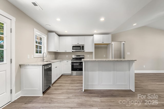 1234 Goodnight Ln, Kannapolis, NC 28081 - kitchen featuring stainless steel appliances, light wood-style floors, a center island, white cabinetry, and light stone counters
