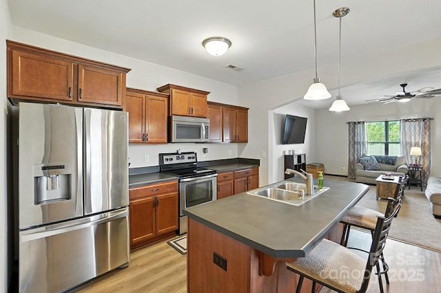 8152 Chilkoot Ln, Locust, NC 28097 - kitchen featuring appliances with stainless steel finishes, dark countertops, light wood-style floors, open floor plan, and a kitchen breakfast bar