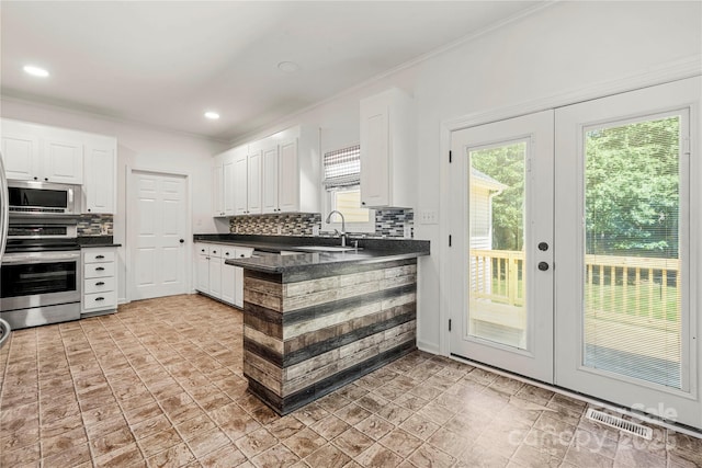 814 Carved Oak Ct, York, SC 29745 - kitchen featuring appliances with stainless steel finishes, dark countertops, white cabinets, decorative backsplash, and ornamental molding