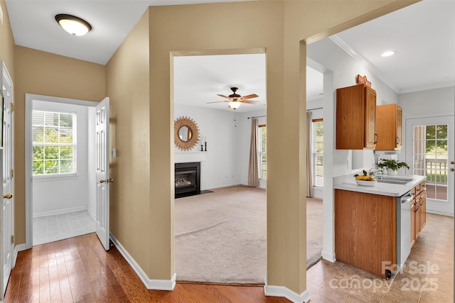 2004 Onotoa Dr, Indian Trail, NC 28079 - kitchen with light countertops, brown cabinetry, a fireplace with flush hearth, dishwasher, and ceiling fan