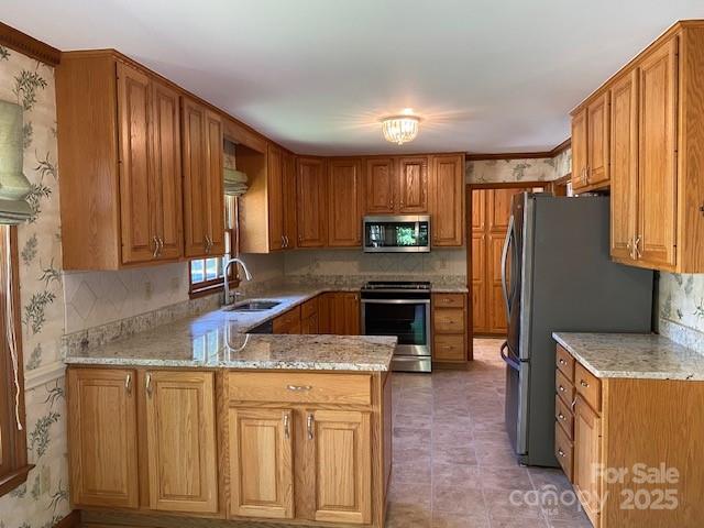 6632 Summer Darby Ln, Charlotte, NC 28270 - kitchen featuring appliances with stainless steel finishes, a peninsula, decorative backsplash, light stone countertops, and brown cabinets