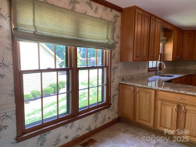 6632 Summer Darby Ln, Charlotte, NC 28270 - kitchen with wallpapered walls, light stone countertops, and brown cabinets