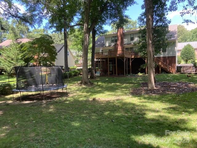 6632 Summer Darby Ln, Charlotte, NC 28270 - view of grassy yard featuring stairs, a trampoline, and a wooden deck