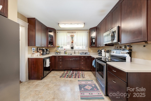 206 Mitchell Ave, Salisbury, NC 28144 - kitchen featuring appliances with stainless steel finishes, glass insert cabinets, light countertops, and dark brown cabinetry
