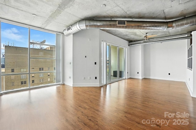 505 E 6th St Unit 908, Charlotte, NC 28202 - spare room featuring wood finished floors, a wall of windows, and a ceiling fan