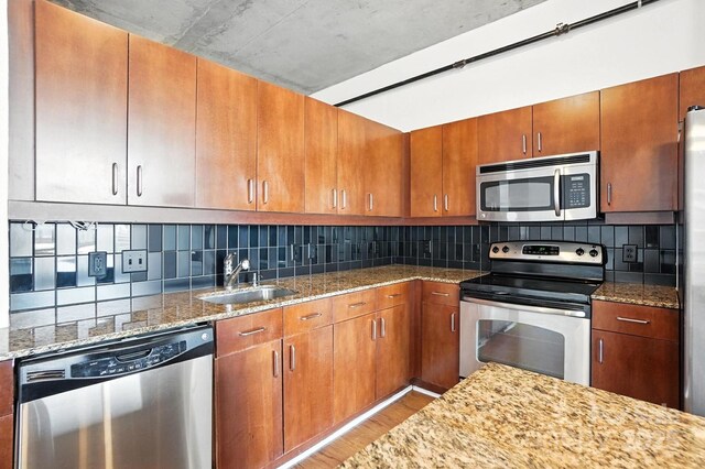 505 E 6th St Unit 908, Charlotte, NC 28202 - kitchen featuring appliances with stainless steel finishes, light wood-type flooring, light stone countertops, and tasteful backsplash
