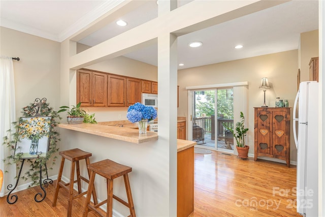 190 Shaws Creek Farm Rd, Hendersonville, NC 28739 - kitchen with white appliances, brown cabinetry, light countertops, a kitchen bar, and crown molding