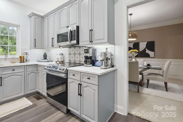 9954 Mitchell Glen Dr, Charlotte, NC 28277 - kitchen with stainless steel appliances, wood finished floors, backsplash, light countertops, and crown molding