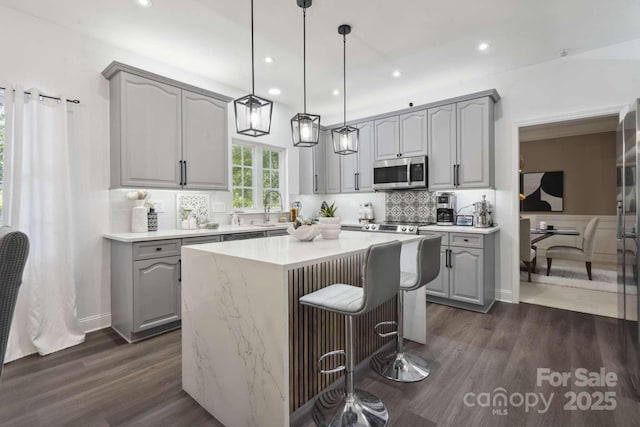 9954 Mitchell Glen Dr, Charlotte, NC 28277 - kitchen with stainless steel microwave, gray cabinets, dark wood-style flooring, backsplash, and a kitchen island