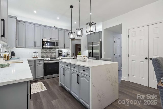 9954 Mitchell Glen Dr, Charlotte, NC 28277 - kitchen featuring appliances with stainless steel finishes, gray cabinets, a kitchen island, dark wood-type flooring, and recessed lighting