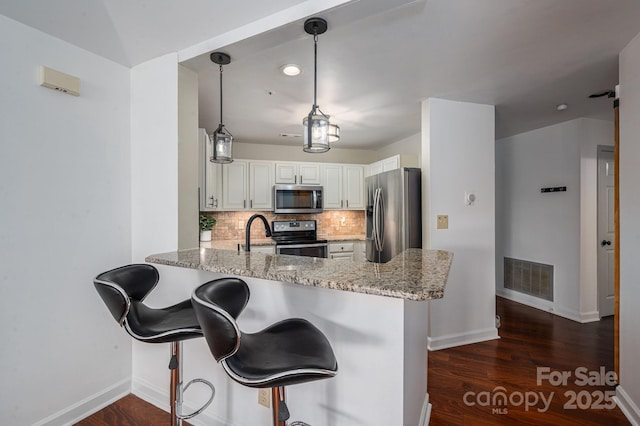 1018 SW Dr SW Unit 18, Davidson, NC 28036 - kitchen with stainless steel appliances, a peninsula, light stone counters, decorative backsplash, and dark wood-style flooring