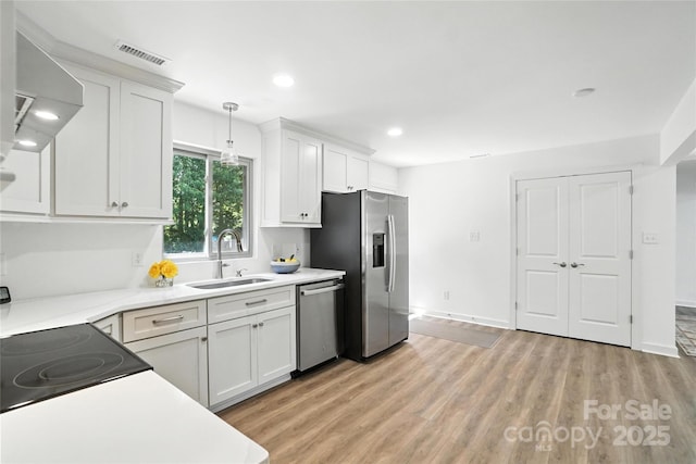 2705 Lowell Bethesda Rd, Gastonia, NC 28056 - kitchen with appliances with stainless steel finishes, light countertops, light wood-style floors, white cabinetry, and hanging light fixtures