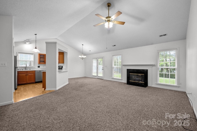 385 Glensprings Dr Unit 269, Fletcher, NC 28732 - unfurnished living room with light carpet, vaulted ceiling, a fireplace with flush hearth, ceiling fan, and a chandelier