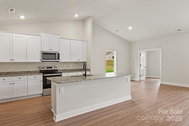 7106 Jerimoth Dr, Charlotte, NC 28215 - kitchen with stainless steel appliances, white cabinets, a kitchen island with sink, light wood-style floors, and light stone counters