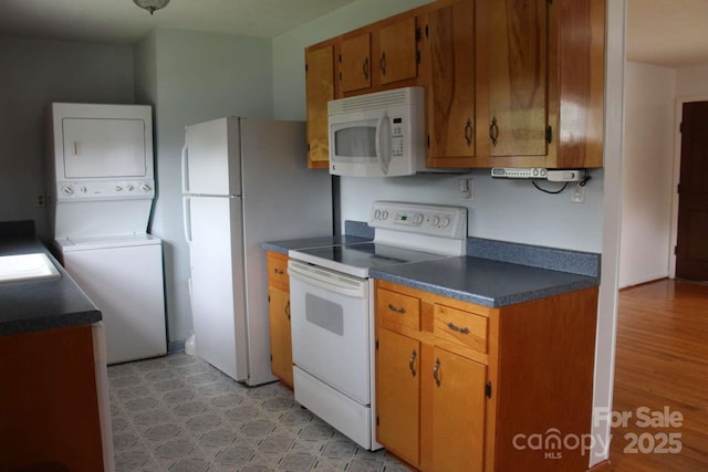 50 Huffman Rd, Asheville, NC 28806 - kitchen with white appliances, dark countertops, estacked washer and dryer, and brown cabinets