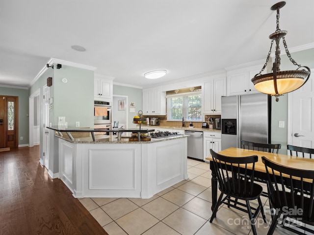 165 Cottontail Ln SE, Concord, NC 28025 - kitchen featuring appliances with stainless steel finishes, ornamental molding, white cabinetry, dark stone countertops, and decorative light fixtures