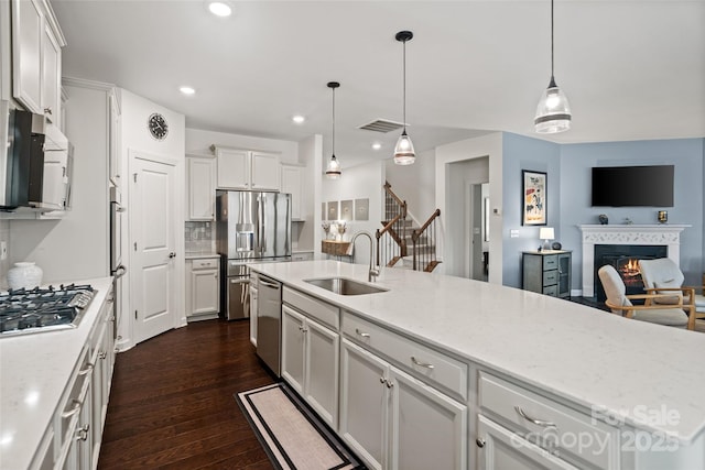 17733 Burnt Hickory Dr, Charlotte, NC 28278 - kitchen featuring stainless steel appliances, dark wood-type flooring, open floor plan, a glass covered fireplace, and white cabinets
