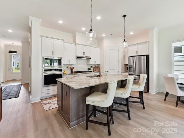 1120 Idyllic Ln, Waxhaw, NC 28173 - kitchen featuring appliances with stainless steel finishes, decorative backsplash, crown molding, under cabinet range hood, and a breakfast bar area
