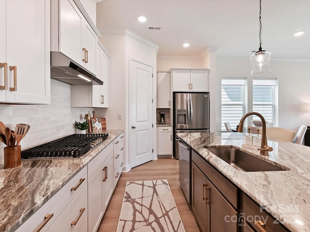 1120 Idyllic Ln, Waxhaw, NC 28173 - kitchen featuring under cabinet range hood, stainless steel appliances, light wood-type flooring, hanging light fixtures, and tasteful backsplash