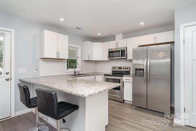 213 Pinewood Dr, Grover, NC 28073 - kitchen featuring appliances with stainless steel finishes, a peninsula, healthy amount of natural light, white cabinets, and recessed lighting