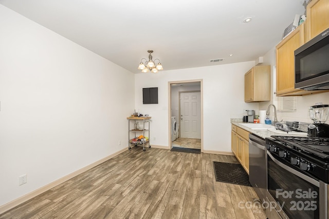 1019 Richard St, Salisbury, NC 28144 - kitchen with stainless steel appliances, light brown cabinets, light wood-style flooring, washer / clothes dryer, and a chandelier