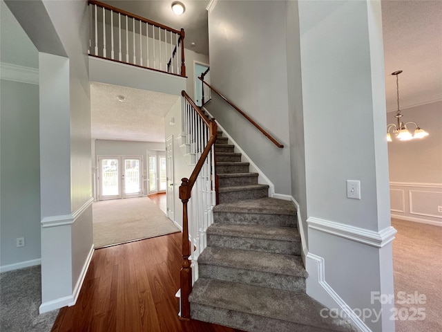 2609 Lamp Post Ln, Kannapolis, NC 28081 - stairway with carpet floors, ornamental molding, a chandelier, wood finished floors, and a wainscoted wall