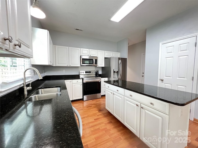 2609 Lamp Post Ln, Kannapolis, NC 28081 - kitchen with stainless steel appliances, light wood finished floors, white cabinets, and a kitchen island