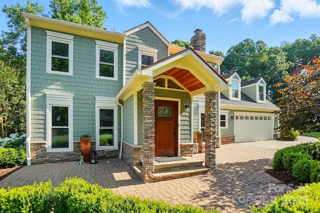 4825 Deanscroft Dr, Charlotte, NC 28226 - view of front facade with stone siding, an attached garage, a chimney, and decorative driveway