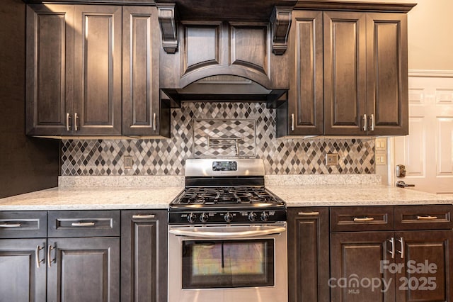 3889 Mattingly Dr, Hickory, NC 28602 - kitchen with stainless steel range with gas stovetop, dark brown cabinets, decorative backsplash, and premium range hood
