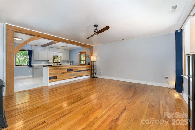 24 Arco Rd, Asheville, NC 28805 - unfurnished living room featuring ceiling fan, light wood-style floors, arched walkways, and beam ceiling