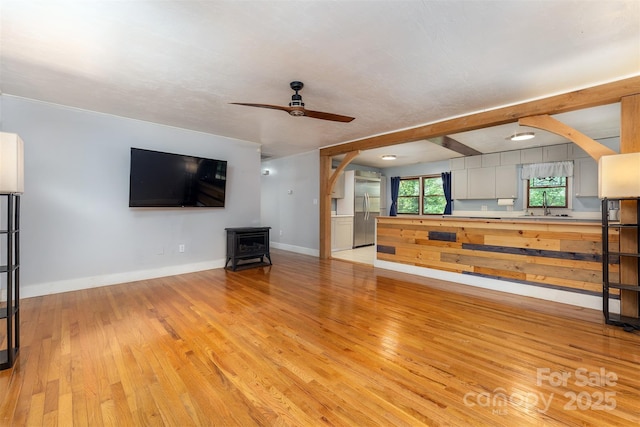 24 Arco Rd, Asheville, NC 28805 - unfurnished living room featuring a wood stove, arched walkways, light wood-style floors, and ceiling fan