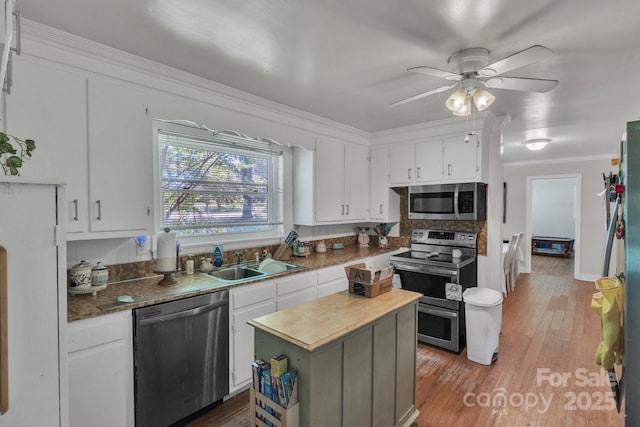 2008 Kimway Dr, Matthews, NC 28105 - kitchen with appliances with stainless steel finishes, white cabinets, crown molding, a ceiling fan, and light wood-type flooring